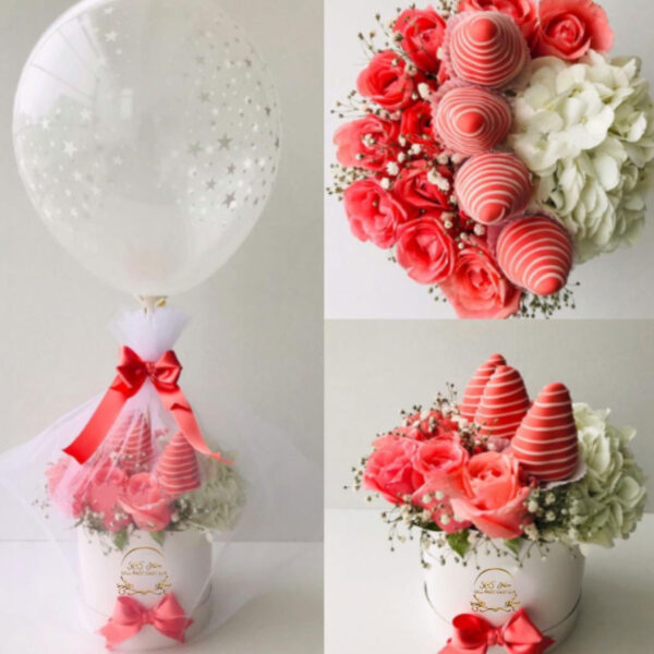 caja redonda con rosas y flores blancas acompañada de fresas con chocolate envuelta en tul, globo y tarjeta